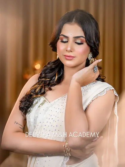 An elegant party look featuring a white saree with gold sequin work. The eye makeup is dramatic with a gold shimmer, paired with a soft lip.