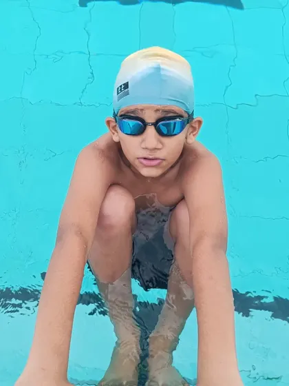 The focused expression of a young swimmer, ready and waiting for his turn in the water. This mental preparation is a critical part of competitive training.