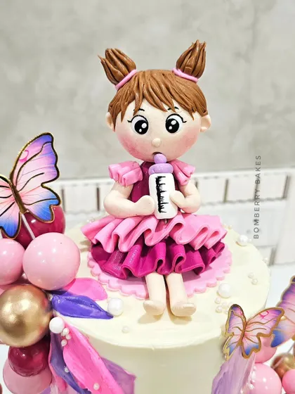 A close-up of the hand-sculpted girl figurine with pigtails and a pink dress.