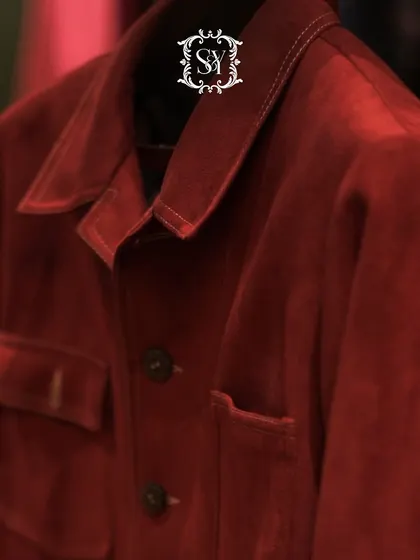 Style that builds confidence through simplicity and strength. A close-up of a deep red jacket, showcasing its rich texture and our signature brand emblem.