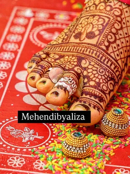 A beautiful, dark henna stain on a bride's foot. The rich color makes the intricate details of the peacock and paisley design stand out perfectly.