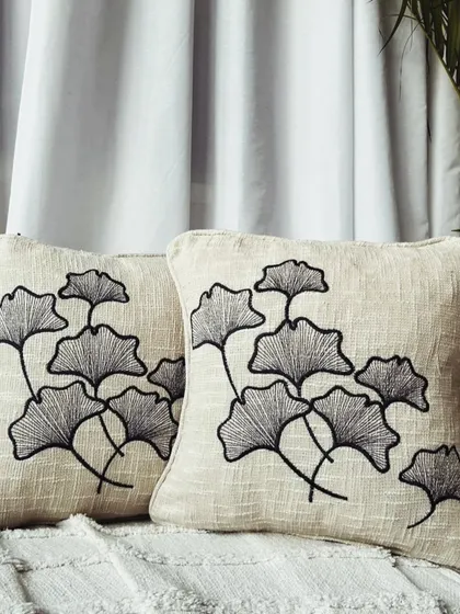 An elegant cushion cover with black embroidered ginkgo leaves. This design offers a sophisticated, minimalist take on nature-inspired decor.