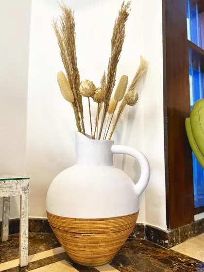 The 'Kerok' vase, with its white pitcher shape and natural bamboo base, is perfect for styling a cozy corner with dried grasses.