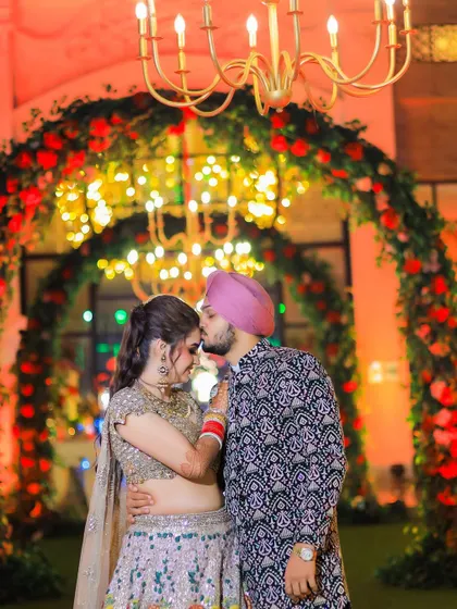 A romantic close-up of the groom kissing the bride's forehead. This tender moment, framed by the festive lights and decor, is a memory to be cherished forever.