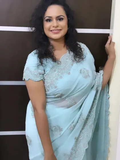 A smiling portrait of the completed party look. The makeup enhances her features while letting her natural curls frame her face beautifully.