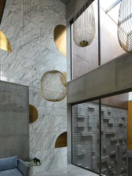 The informal living area on the first floor of Swatantra Residence is a multi-level design. Custom birdcage-like chandeliers hang in the double-height space, adding visual interest and drawing the eye upward.