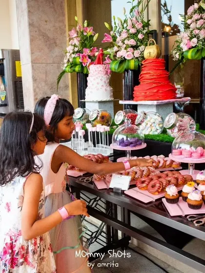 A full view of a lavish dessert spread for a princess party. The table is filled with donuts, cupcakes, and macarons, all beautifully arranged to create a feast for the eyes and the sweet tooth.