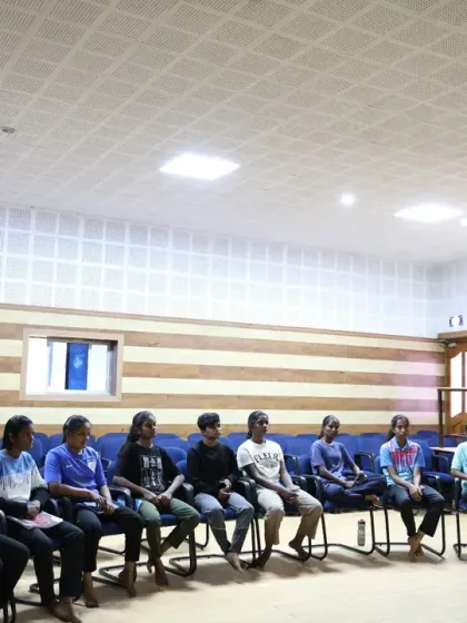 A group of young athletes sits in a semi-circle, fully engaged in a discussion. This format fosters a collaborative learning environment where participants can share experiences and learn from one another.