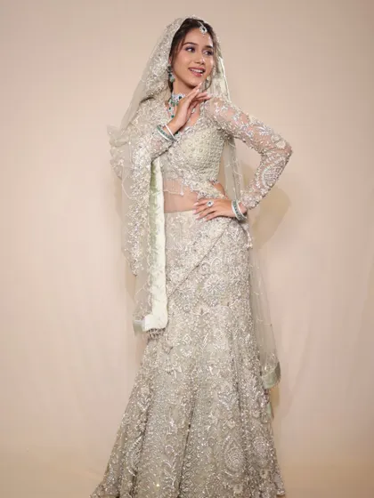 A full-length shot of this stunning pastel creation. The mermaid-style lehenga and long-sleeved blouse are the epitome of modern bridal fashion.