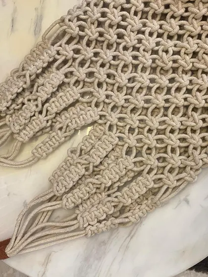 Another close-up of the handles and the top section of the macrame net tote, showing how the straps are securely integrated into the bag's body.