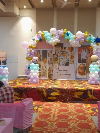 The final stage setup for a 'Naming Ceremony' with a Boss Baby theme, featuring a custom photo backdrop and a pastel balloon arch.