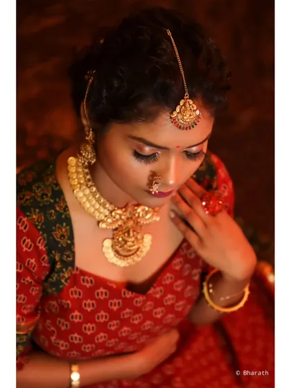 This close-up shot captures the intricate details of the temple jewelry and the rich textures of the traditional outfit.