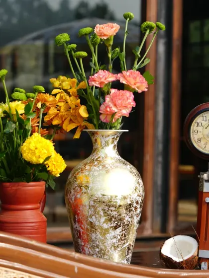 A beautiful still life of decor elements, including a vintage clock, a coconut, and colorful flowers in rustic vases.