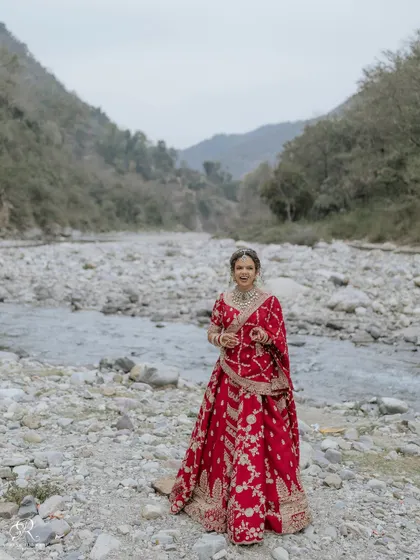 A duplicate of ID 1, a stunning full-length portrait of the bride in her red lehenga against the Rishikesh landscape.