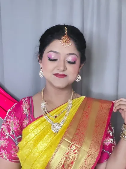 A stunning look for a family function. This client is wearing a traditional yellow and pink silk saree, and I created a matching pink-toned eye makeup look with a radiant base and a classic updo.