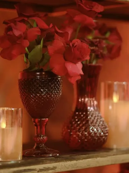 An even tighter shot of the bar back, focusing on the texture of the red glassware and the soft light of the candles.