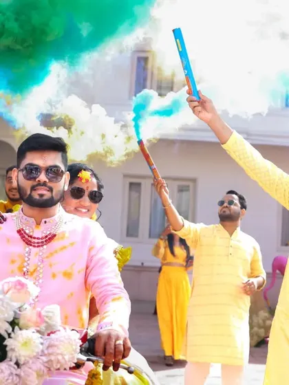 A grand entrance on a decorated bike at a Haldi ceremony, complete with friends setting off colorful smoke bombs. This is how you make an entrance.