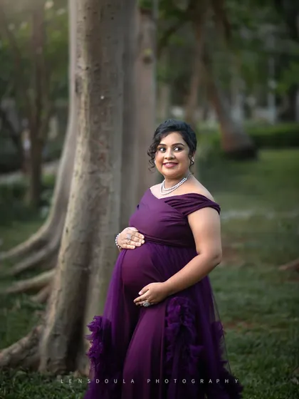 A quiet moment of reflection for the mother-to-be, cradling her bump in a peaceful, wooded setting.