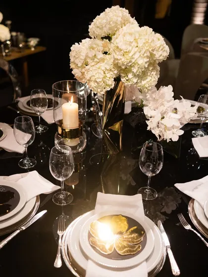 A detailed shot of a place setting, featuring a custom gold-leaf accent on the plate that perfectly matches the glamorous theme of the evening.