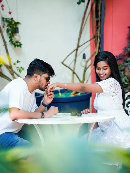 A classic, chivalrous moment with the groom kissing his partner's hand at a cafe table.
