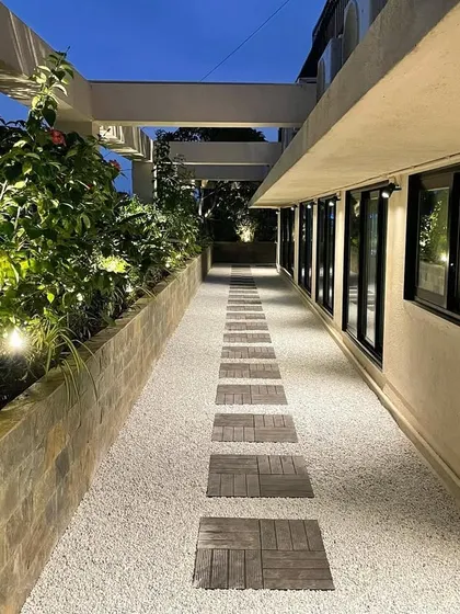 A long shot of the revamped corporate terrace at dusk. The linear path with embedded lights guides the eye and creates a sense of length, while the illuminated planters add warmth and drama.