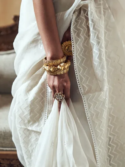We focus on the details that tell a larger story. This image highlights the texture of the saree fabric against the intricate design of the traditional gold bangles, conveying a sense of heritage and luxury.