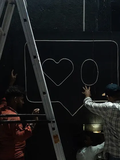 Behind the scenes of the 'Surfing' installation at MUAF. Here, my team and I are mounting the framework for the neon sign against a black brick wall.