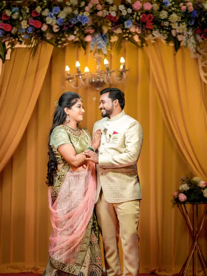 A happy couple portrait that also highlights the beautiful floral and chandelier decor of the reception stage.
