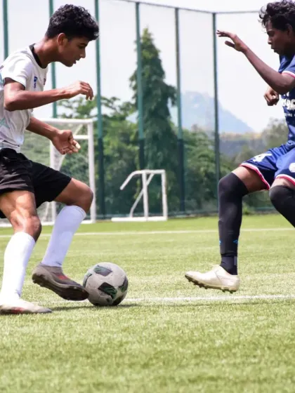 A young footballer skillfully shields the ball from a defender during a practice match. These game simulations are crucial for developing tactical awareness and on-field decision-making.