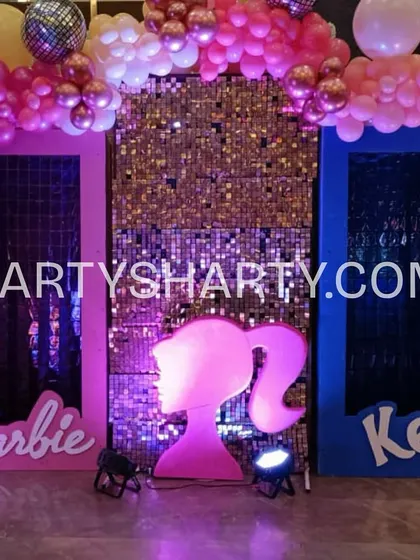 A fun photo opportunity with life-sized Barbie and Ken doll boxes, set against a glittering gold sequin wall and topped with a pink balloon arch.