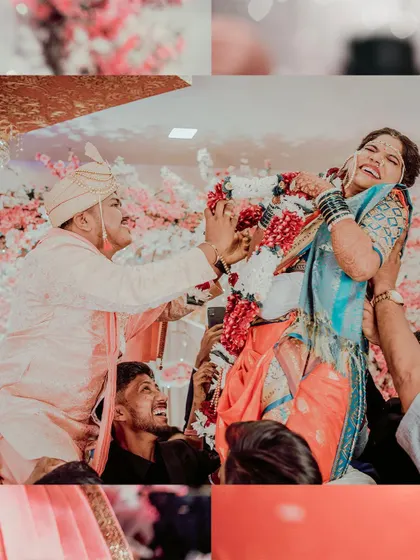 The fun and games of a wedding. The groom lifts the bride during the varmala ceremony, a moment of pure joy and celebration surrounded by family.