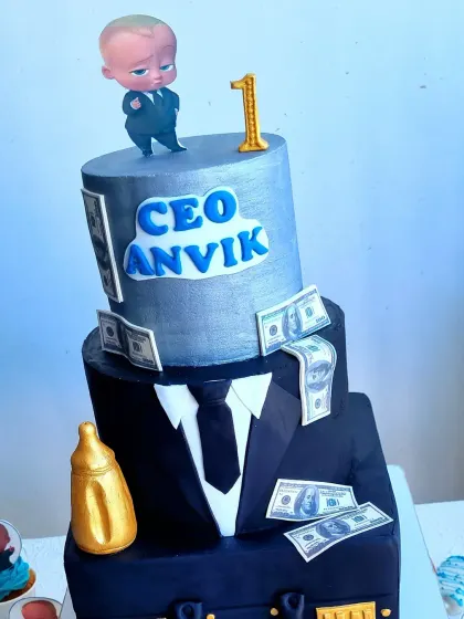 A close-up of a three-tier Boss Baby cake. This sculpted cake features a suit, a briefcase, and a "CEO" nameplate, perfect for a first birthday.