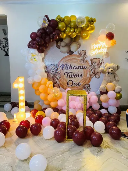 Here is a teddy bear themed first birthday party setup. I used a warm color palette of maroon, orange, and gold balloons, a custom printed backdrop, a large teddy bear prop, and a light-up number one to complete the look.