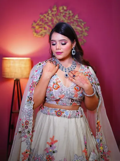 A close-up of the white floral lehenga, showing the colorful embroidery and the stunning necklace.