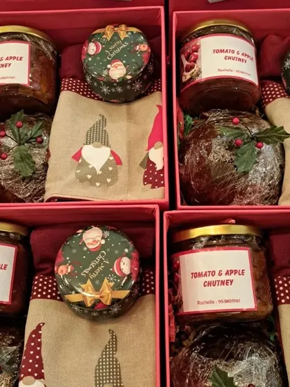 A close-up view of the contents inside four of my Christmas hampers. You can see the rich, dark Christmas pudding and the festive gnome-themed kitchen towels that add a touch of whimsy.
