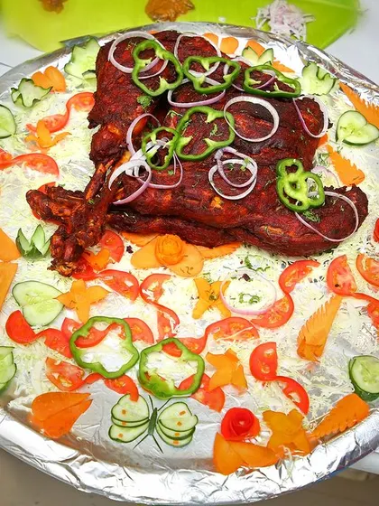 A platter of roasted mutton, garnished with fresh vegetables and bell peppers. We take great care in making our food look as good as it tastes.
