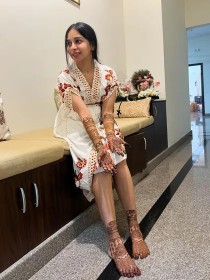 A beautiful bride, Maheshwari, relaxing after her mehendi session, with intricate designs on her hands and feet.
