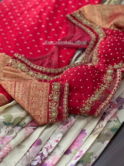 A red blouse with a brocade sleeve cuff and sheer panel.