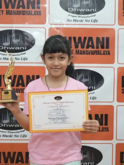 A young student proudly displays her certificate and trophy.