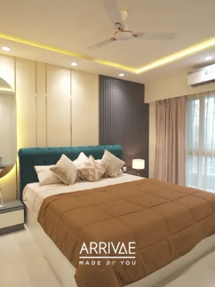 This bedroom features a striking teal tufted headboard that adds a pop of color. The wall paneling and cove lighting on the ceiling add depth and a touch of modern luxury.