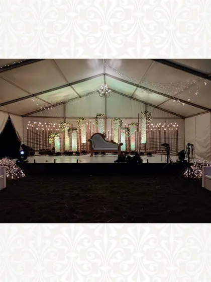 A wider view of the vintage-themed tent setup. The combination of the elegant stage, open space, and simple white guest sofas creates a chic and sophisticated atmosphere.