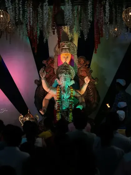 A view from the crowd looking up at the Palmbeach Cha Vighnaharta idol, capturing the perspective of a devotee.