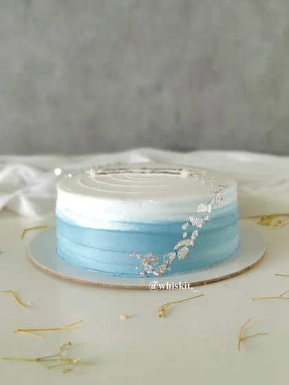 A blue ombre flat cake with silver leaf accents, creating a simple yet beautiful design reminiscent of a calm ocean.