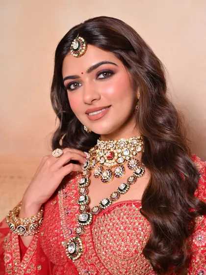 A classic bridal portrait in a red lehenga, featuring soft waves and a timeless makeup look with a nude lip and defined eyes.