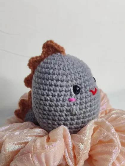 A grey dino keychain, ready for adoption.