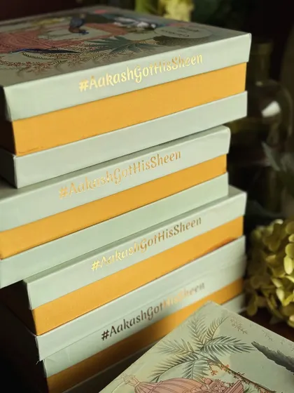 A stack of our custom wedding favor boxes, each one foil stamped with the couple's unique hashtag, #AakashGotHisSheen. We love adding these personal details to make your wedding gifts truly one of a kind.