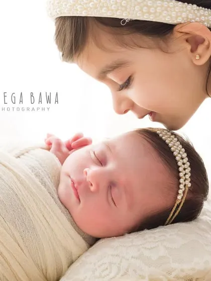 A close-up of a big sister's gentle kiss on her newborn sister's forehead. This is the kind of precious, fleeting moment I love to preserve.