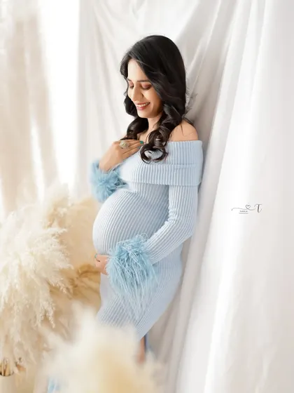 A soft and dreamy portrait. The mom-to-be is surrounded by pampas grass, her light blue feathered dress adding a touch of unique texture.