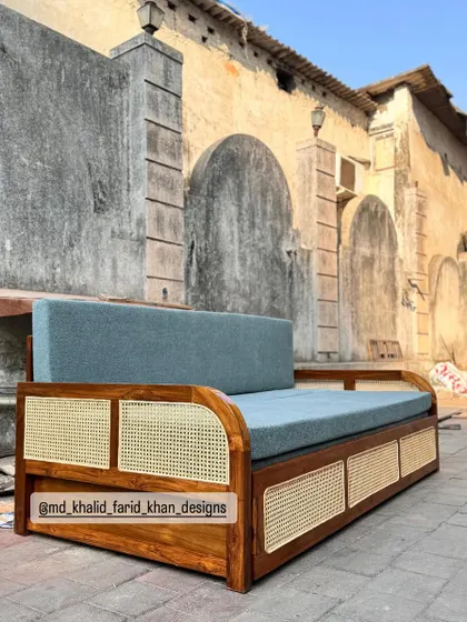 The sofa-cum-bed in its closed position, serving as a stylish daybed with a solid teak and cane frame.
