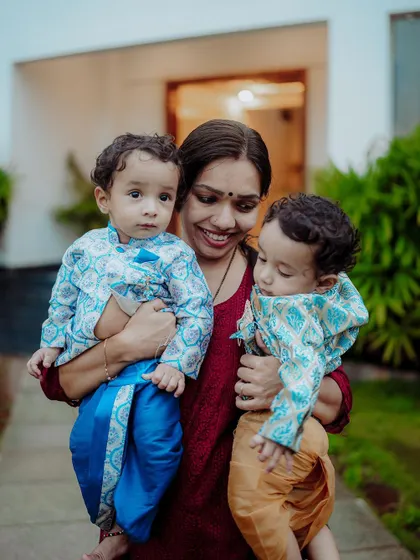 Capturing the bond between a mother and her children is a privilege. This outdoor portrait shows a mother holding her twin boys, dressed in traditional attire, creating a warm and authentic family moment.